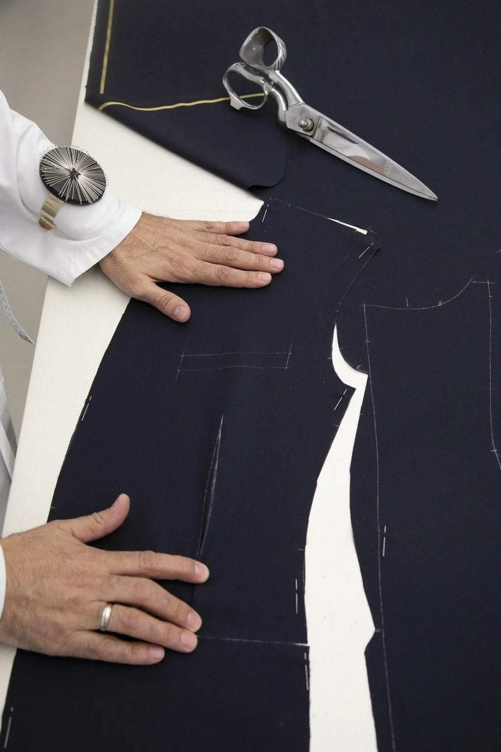 Tailor cutting and marking navy fabric on the cutting table